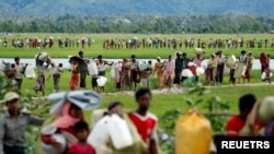 FILE - Rohingya refugees, who crossed the border from Myanmar two days before, walk after they received permission from the Bangladeshi army to continue on to the refugee camps, in Palang Khali, near Cox's Bazar, Bangladesh, Oct. 19, 2017.