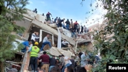 Pejabat dan tim SAR melakukan pencarian korban di sebuah bangunan yang runtuh akibat gempa yang mengguncang Laut Aegea, Jumat (30/10) dan merobohkan sejumlah bangunan di provinsi pesisir Izmir, Turki, 30 Oktober 2020.