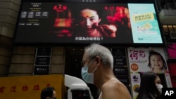 资料照：人们走过在香港市中心街道旁巨大电子屏幕上播放的电影“花木兰”的海报。( 2020 年 9 月 17 日)
