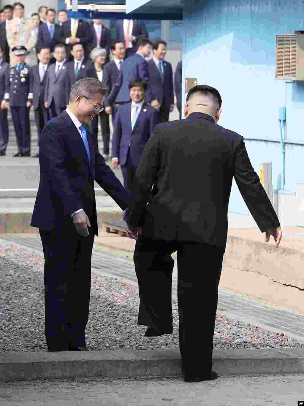 Pemimpin Korea Utara Kim Jong Un menyeberangi garis demarkasi militer untuk bertemu dengan Presiden Korea Selatan di Desa Panmunjom, di Zona Demiliterisasi, 27 April 2018.