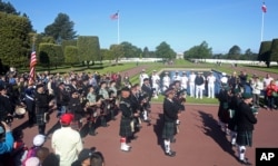 Visitors and cadets from the U.S. Naval Academy, in the background, watch a bagpipe band parading at the Colleville American military cemetery in Colleville-sur-Mer, western France, as part of the commemoration of the 71st anniversary of the D-Day landing