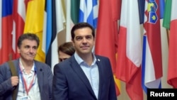 Perdana Menteri Yunani Alexis Tsipras (tengah) dan Menteri Keuangan Yunani Euclid Tsakalotos meninggalkan KTT pemimpin zona euro di Brussels, Belgia (13/7). 