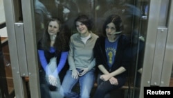 Members of the female punk band 'Pussy Riot' sit in a glass-walled cage before a court hearing in Moscow, October 1, 2012. 