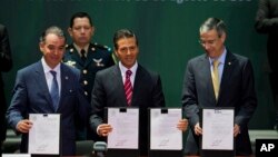 Mexican President Enrique Pena Nieto, center, Senate leader Raul Cervantes Andrade, left, and House Speaker Jose Gonzalez Morfin hold up signed documents at a ceremony to mark the signing of a historic energy reform bill, at the National Palace in Mexico City, Aug. 11, 2014.
