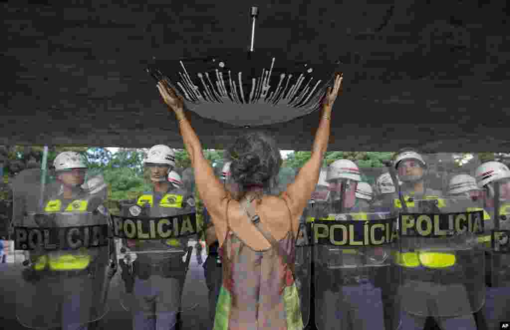 A demonstrator holds an upturned umbrella before a cordon of police during a protest against the rationing of water in Sao Paulo, Brazil, Feb. 11, 2015.