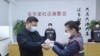 中国国家主席习近平戴着口罩视察北京安华里小区时一名防疫人员检测他的体温。（2020年2月10日）