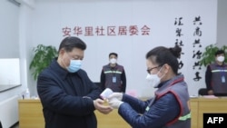 中国国家主席习近平戴着口罩视察北京安华里小区时一名防疫人员检测他的体温。（2020年2月10日）