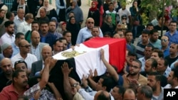 FILE - People carry the coffin, covered with the an Egyptian flag, of police Captain Ahmed Fayez at Al-Hosary mosque in Cairo, Oct. 21, 2017. Fayez was killed Oct. 20 in a gunbattle with militants in al-Wahat al-Bahriya area in Giza province, about 135 kilometers (84 miles) southwest of Cairo.