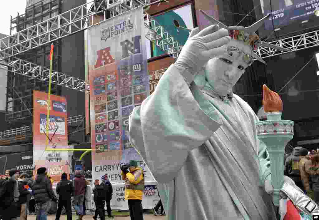 A man dressed as the Statue of Liberty poses for photos with football fans along Super Bowl Boulevard. Jan. 31, 2014, in New York. T