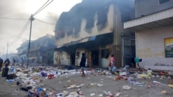 Orang-orang berdiri di tengah puing-puing di depan gedung yang terbakar setelah berhari-hari kerusuhan di Honiara, Kepulauan Solomon, 26 November 2021. (Foto: REUTERS/Elizabeth Osifelo)