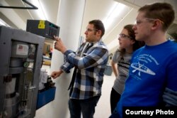 Andrew Brunn (left), a civil engineering major, works with a measurement device in the Northeastern University Civil Engineering Lab as civil engineering majors Sarah Thomas (center) and Peter Calves (right) look on.