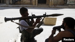 Free Syrian Army fighter waits for Syrian Army tanks to advance in the Salaheddin neighborhood in central Aleppo, Aug. 10, 2012.