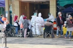 Sejumlah pasien COVID-19 menunggu giliran pendataan dan perawatan di depan pintu masuk RSUD Bekasi, 30 Juni 2021. (Foto: VOA/Indra Yoga)