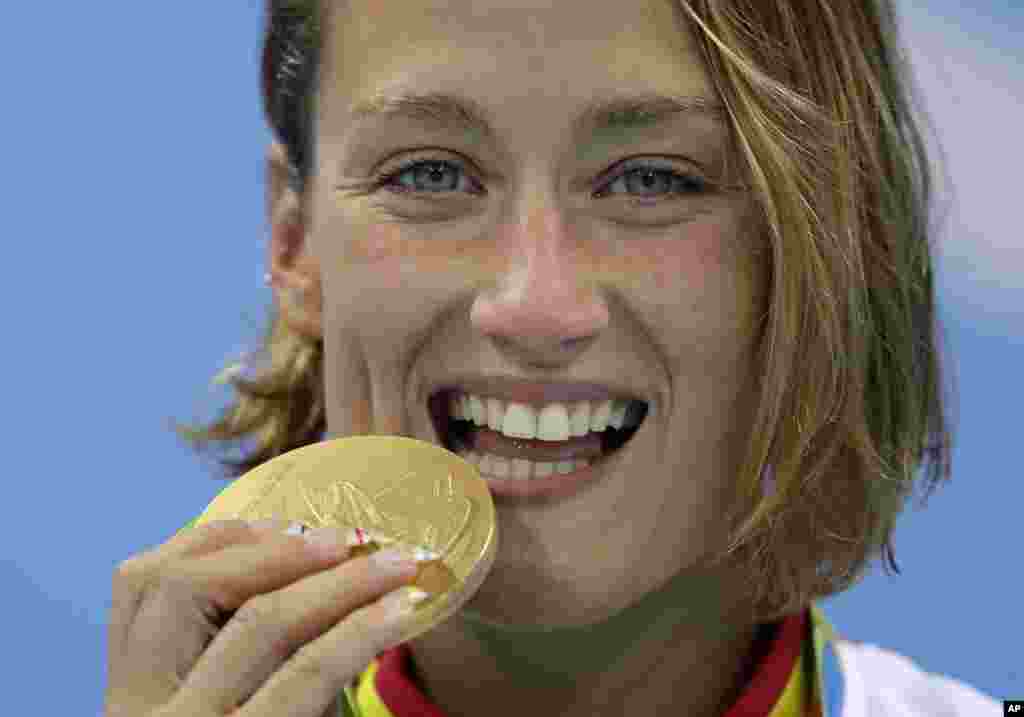 Spain's Mireia Belmonte Garcia bites her gold medal during the women's 200-meter butterfly medals ceremony during the swimming competitions at the 2016 Summer Olympics, Wednesday, Aug. 10, 2016.