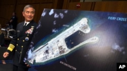 FILE - Adm. Harry B. Harris, Jr., US Navy Commander, U.S. Pacific Command walks past a photograph showing an island that China is building on the Fiery Cross Reef in the South China Sea, as the prepares to testify on Capitol Hill in Washington, Sept. 17, 2015, 