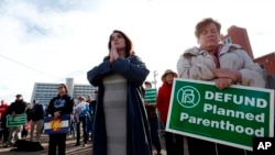 Los participantes en una manifestación anti-aborto tienen señales y oran mientras escuchan a un miembro del clero cristiano leer en la Biblia, frente a Planned Parenthood of the Rocky Mountains, en Denver, el sábado 11 de febrero de 2017.