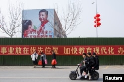 Men ride a scooter past a poster showing Chinese President Xi Jinping on the side of a school building in Henan province, China February 22, 2019.