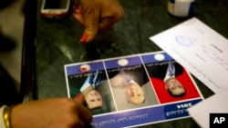 FILE - A woman votes for President Bashar al-Assad by marking the ballot with blood from her pricked finger, in Damascus, Syria, June 3, 2014.