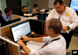 FILE - Puerto Rico Health Department workers monitor social media for Zika related issues at the department's headquarters in San Juan, Puerto Rico.