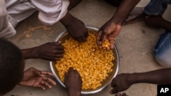 Migrants share a bowl of pasta during their lunch at the courtyard of a detention center for migrants, in the village of Karareem, around 50 kilometers from Misrata, Libya, Sept. 25, 2016. Libya is an important transit and destination country for migrants who arrive seeking employment or a path to Europe.