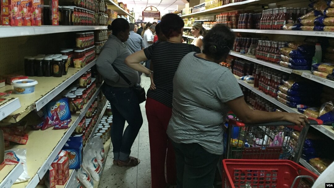 Muchos compradores pasan horas haciendo colas para poder adquirir los productos que buscan. [Foto: VOA].