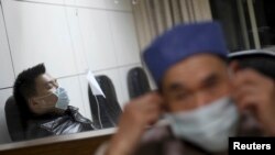 A patient (L) with fever receives treatment at the hospital where a 67-year-old H7N9 patient is being treated, in Hangzhou, Zhejiang province, April 3, 2013. 