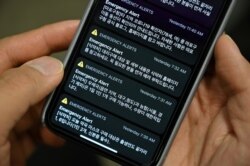 This photo illustration shows a man holding her phone showing emergency alert text messages announcing locations that confirmed COVID-19 patients have visited, among others, in Seoul on March 10, 2020.