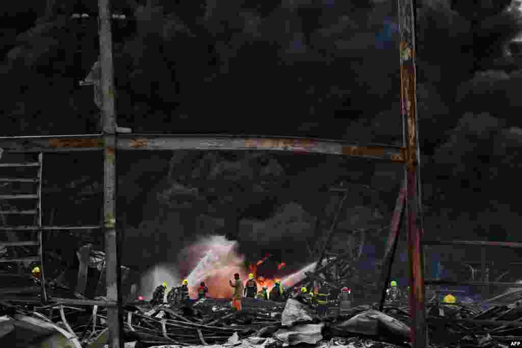 Firefighters work at the site of an explosion and fire at a plastics factory on the outskirts of Bangkok, Thailand.