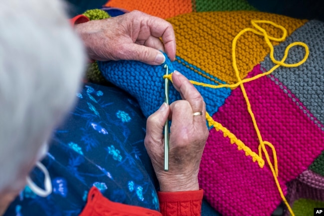 In this photo provided by Edward Boches, a volunteer adds a border to a blanket, Jan. 8, 2023 in Brookline, Mass. The Welcome Blankets will be donated to agencies helping immigrants who recently arrived in the United States. (Edward Boches via AP)