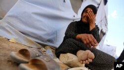 An Iraqi refugee woman from Mosul sits outside her family's tent at Khazir refugee camp outside Irbil, 217 miles (350 kilometers) north of Baghdad, June 13, 2014.