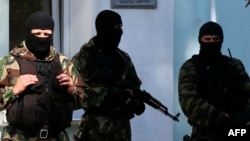 FILE - Armed men stand guard in front of the entrance of the Mejlis of the Crimean Tatar people, the single-highest executive-representative body of the Crimean Tatars, in Simferopol, Sept. 16, 2014.