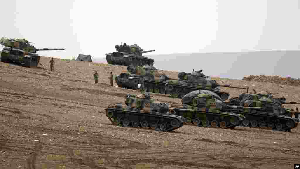 Des soldats turques tiennent leur position avec des chars d&rsquo;assaut au sommet d&rsquo;une colline dans le faubourg de Suruc, à la frontière Turco-Syrienne, observant Kobani, en Syrie, au cours des combats entre les Kurdes Syriens et les combattants de l&rsquo;Etat Islamique, dimanche le 12 octobre 2014. (AP Photo/Lefteris Pitarakis) 