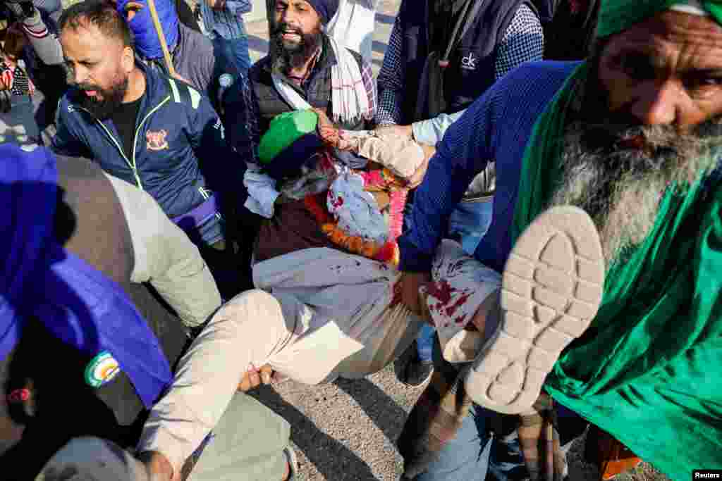 People carry an injured man as farmers march towards New Delhi to press for better crop prices promised to them in 2021, at the Shambhu barrier, a border crossing between Punjab and Haryana states, India.