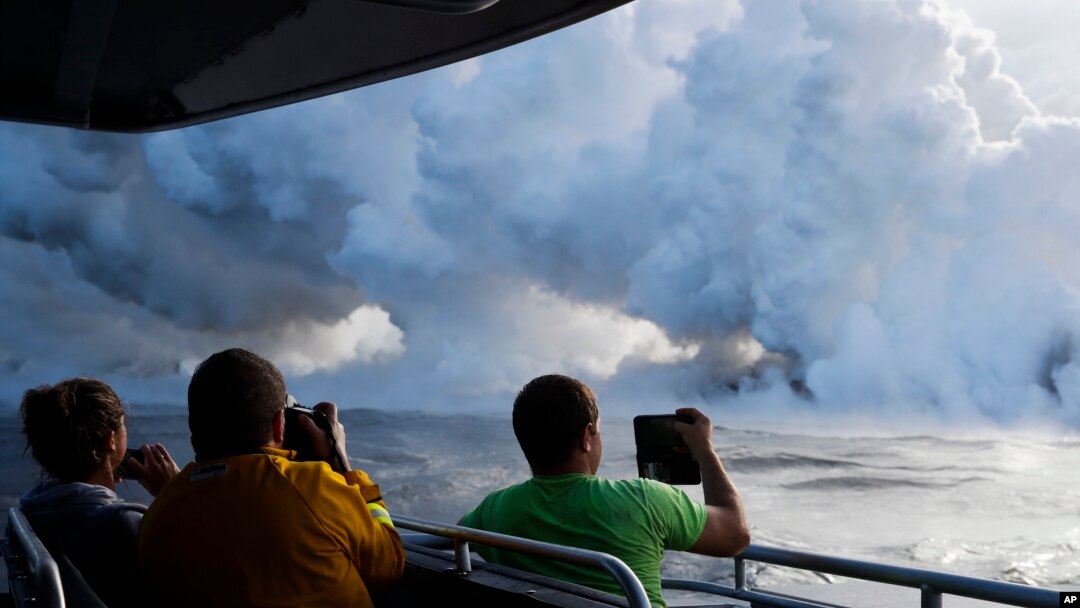  People take pictures as lava enters the ocean, generating plumes of steam near Pahoa, Hawaii Sunday, May 20, 2018.
