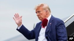 FILE - Former President Donald Trump waves as he steps off his plane at Ronald Reagan Washington National Airport, Aug. 3, 2023, in Arlington, Va. 