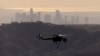 A firefighting helicopter flies past the downtown Los Angeles cityscape as it goes back and forth dropping water on the Eaton Fire burning in the Angeles National Forest, north of Altadena, California, on Jan. 13, 2025.