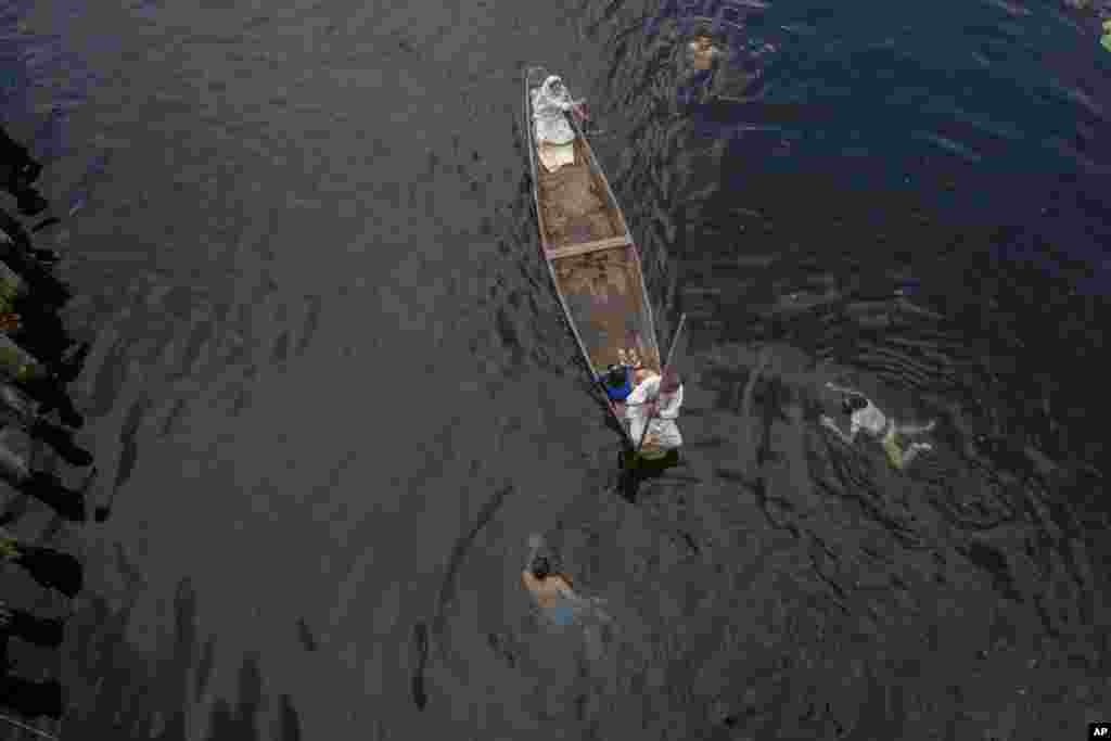 A Kashmiri family row their shikara, or traditional boat, as boys swim in the Nageen Lake on the outskirts of Srinagar, Indian-controlled Kashmir.