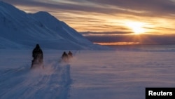 FILE - Scientists drive their snowmobiles cross the arctic towards Kongsfjord during sunset near Ny-Alesund, Svalbard, Norway, April 10, 2023. 