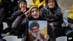 A woman gives a military salute as a trailer carrying the coffins containing the bodies of Hezbollah's former leader Hassan Nasrallah and his cousin and successor Hashem Safieddine drives through the crowd in Beirut, Feb. 23, 2025.