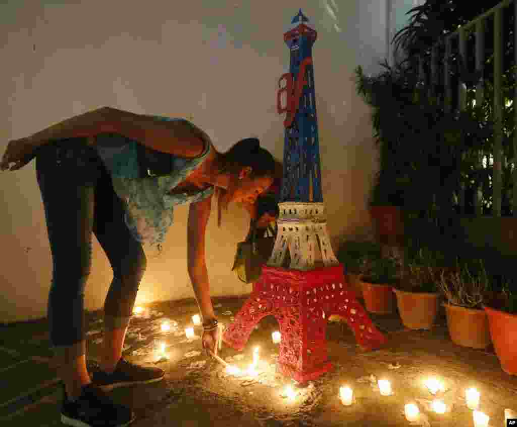 Une française allume des bougies devant une réplique Tour Eiffel à l&rsquo;extérieur de l'Alliance Français en mémoire des victimes des attaques de Paris, lundi 16 novembre 2015 au quartier financier de Makati City, à l'est de Manille, Philippines.