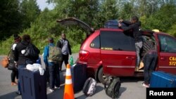 Yon gwoup fanmi ki rive sou fwontyè ant Etazini ak Kanada. Yo di otorte kanadyèn yo se ayisyen yo ye. Yo te soti nan Champlain, New York, 3 Out, 2017. (Foto: Reuters / Christinne Muschi)