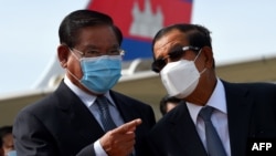 FILE- Cambodia's Minister of Interior Sar Kheng (L) and Prime Minister Hun Sen (R) talk during King Norodom Sihamoni's departure to China for a health check-up at Phnom Penh International Airport in Phnom Penh on October 6, 2020. (Photo by TANG CHHIN Sothy / AFP)