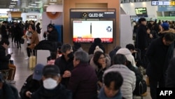 People watch a television screen showing a news broadcast with file footage of a North Korean missile test, at a railway station in Seoul on January 14, 2024.