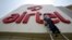 FILE - A worker cleans a logo of Bharti Airtel at its zonal office building in the northern Indian city of Chandigarh.