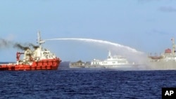 Penjaga Pantai Vietnam merilis foto yang menunjukkan kapal penjaga pantai China (kiri) tengah menembakkan meriam air ke arah kapal Vietnam (kanan), saat kapal penjaga kapal China (tengah) berlayar mengawalnya di Laut China Selatan (7/5).