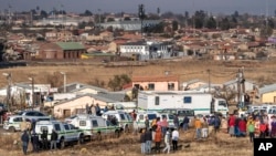 People gather at the scene of an overnight bar shooting in Soweto, South Africa, Sunday July 10, 2022. 