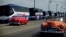 Vintage U.S. cars pass by a fleet of Chinese-made Yutong buses parked at the sea front Malecon in Havana, Feb. 10, 2017.