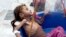 FILE - In this Aug. 25, 2018, image made from video, a severely malnourished girl is weighed at the Aslam Health Center in Hajjah, Yemen.