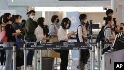 Putnici sa maskama stoje u redu, da bi se ukrcali na svoje letove, na terminalu za domaći saobraćaj na aerodromu Gimpo u Seulu, 27. maja 2020. (Foto: AP)