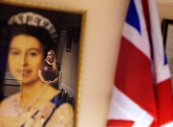 FILE - Lisa Partridge, 28, who grew up with the Protestant Loyal Orange Institution, is reflected in a portrait of Queen Elizabeth II at the Orange Hall, in Portadown, Northern Ireland, Dec. 19, 2019.